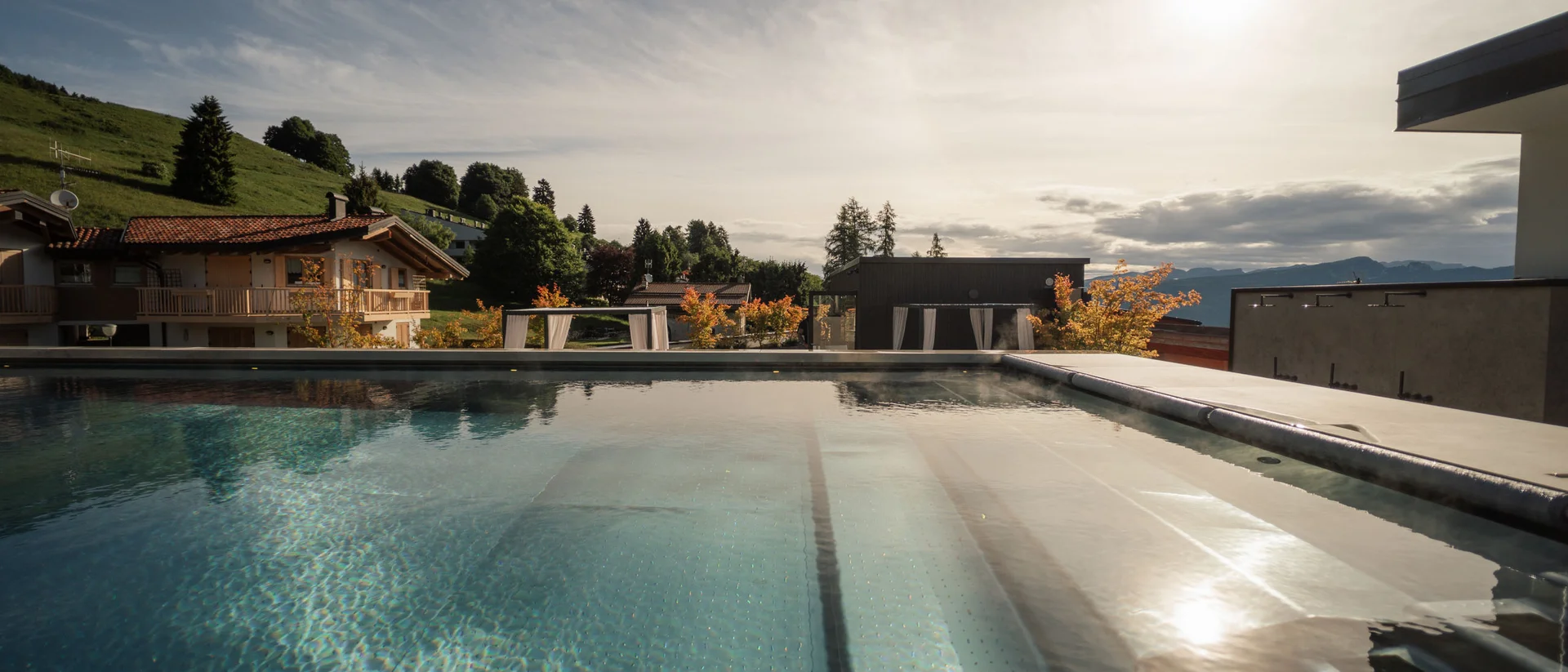 Elgus: hotel con spa a Brentonico Piscina all'aperto con vista su case e colline al tramonto
