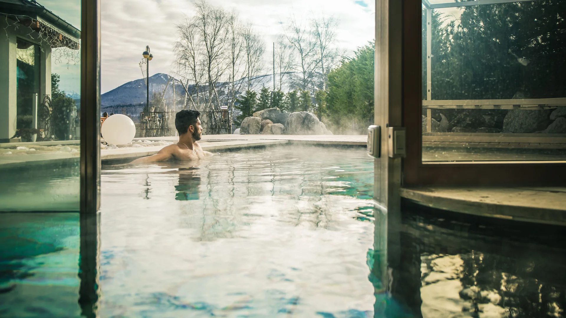 Uomo rilassato in piscina termale con vista sulle montagne