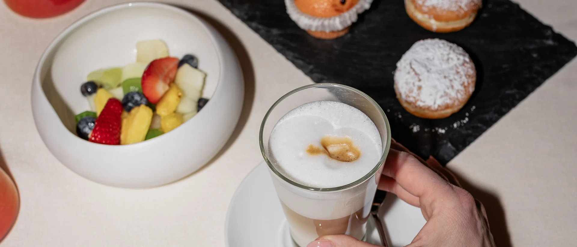 Il nostro ristorante a San Giacomo, Brentonico Colazione con caffè latte, frutta fresca e dolcetti su tovaglia bianca