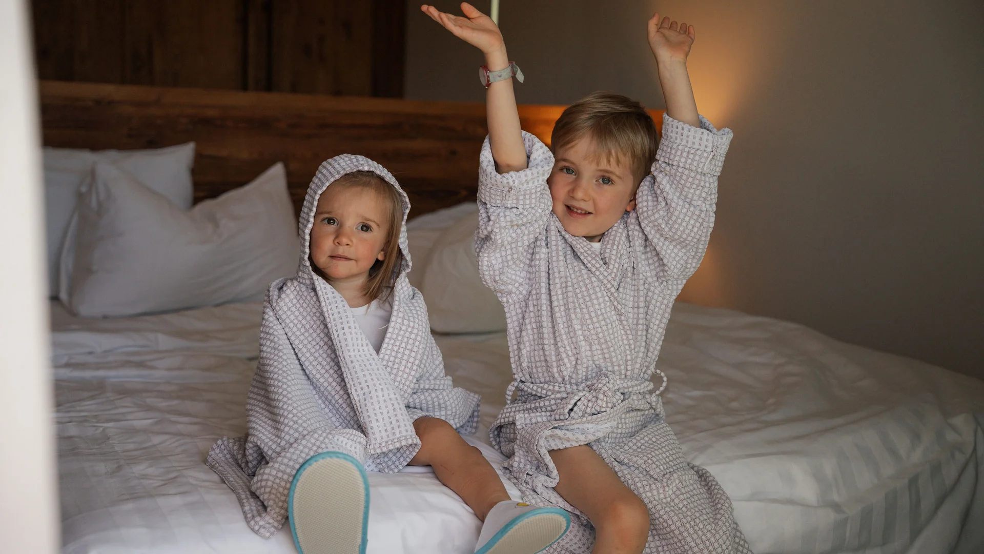 Elgus: hotel a 4 stelle in Trentino Due bambini in accappatoi seduti su un letto in una stanza d'albergo