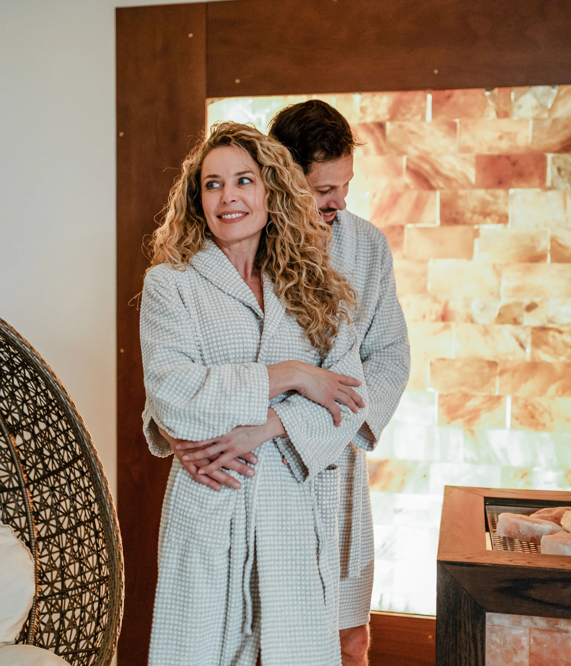 Elgus: hotel con spa a Brentonico Coppia in accappatoi abbracciata in una spa con parete di sale illuminata