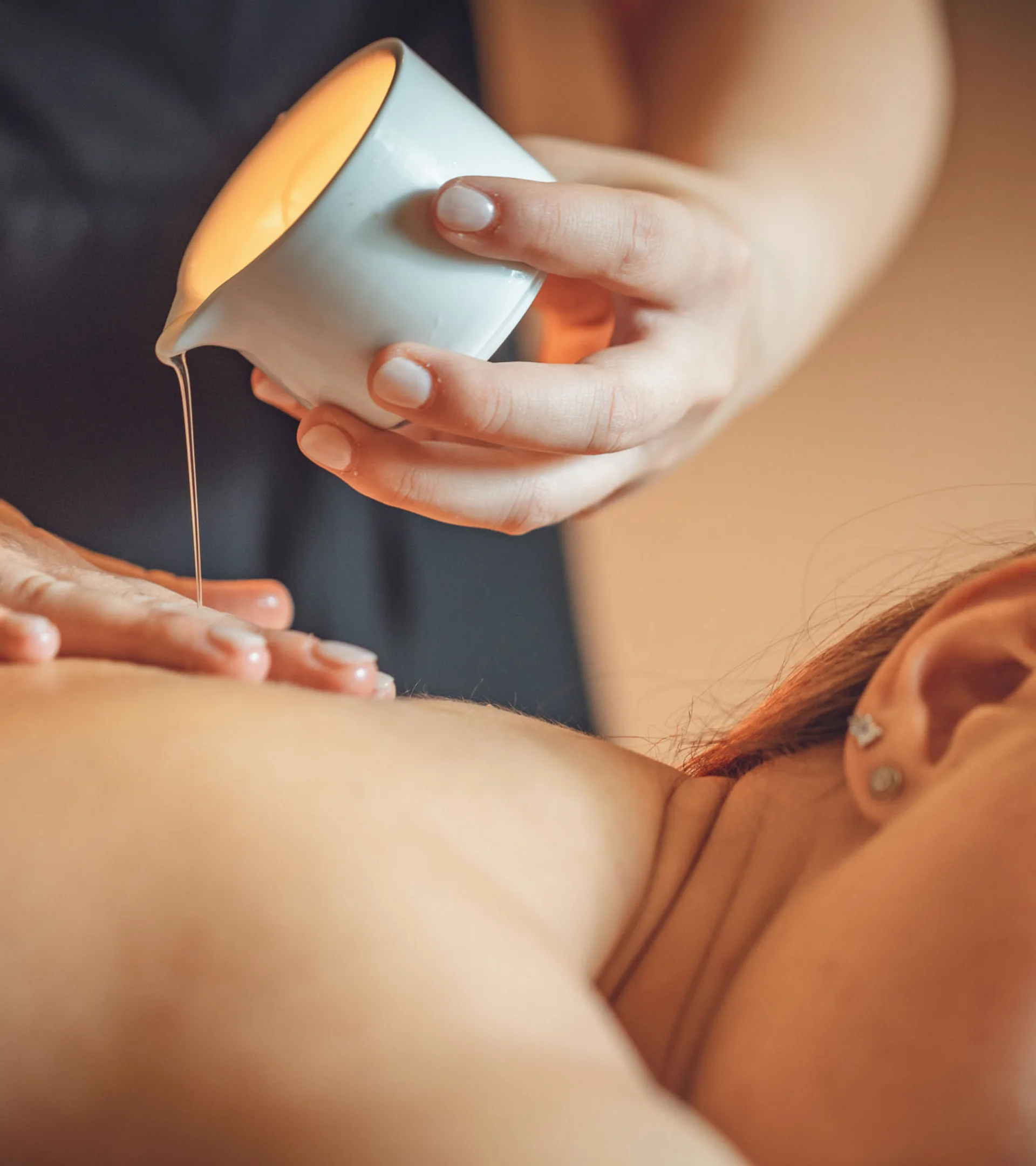 Trattamenti e massaggi in Trentino Olio versato sulla schiena di una donna durante un massaggio rilassante