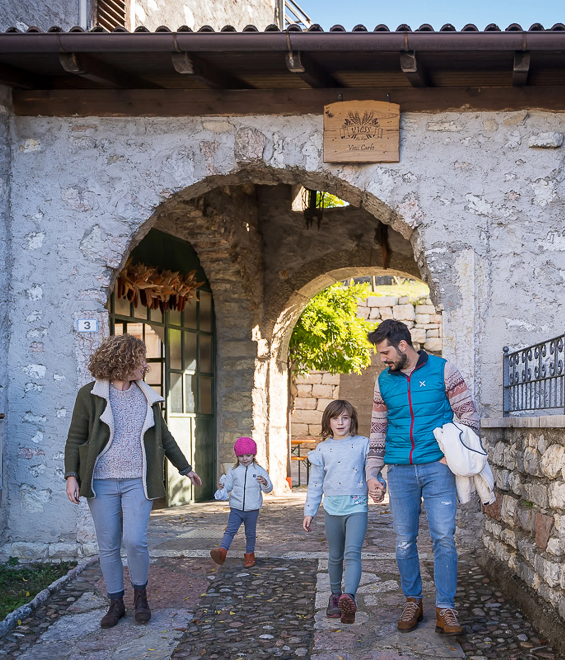 Tutto il divertimento di un hotel sul Monte Baldo Famiglia che cammina sotto un arco in pietra in un villaggio storico