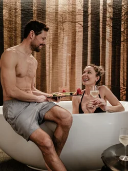 Coppia che si gode un bagno rilassante con vino e frutta in una vasca bianca