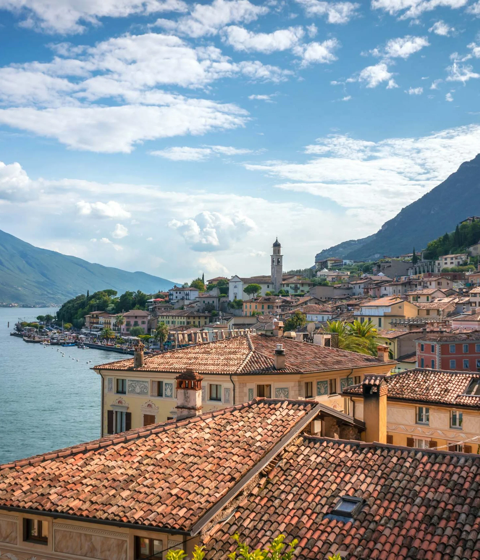 Tutto il divertimento di un hotel sul Monte Baldo Vista panoramica di un borgo con tetti in terracotta sul lago e montagne sullo sfondo