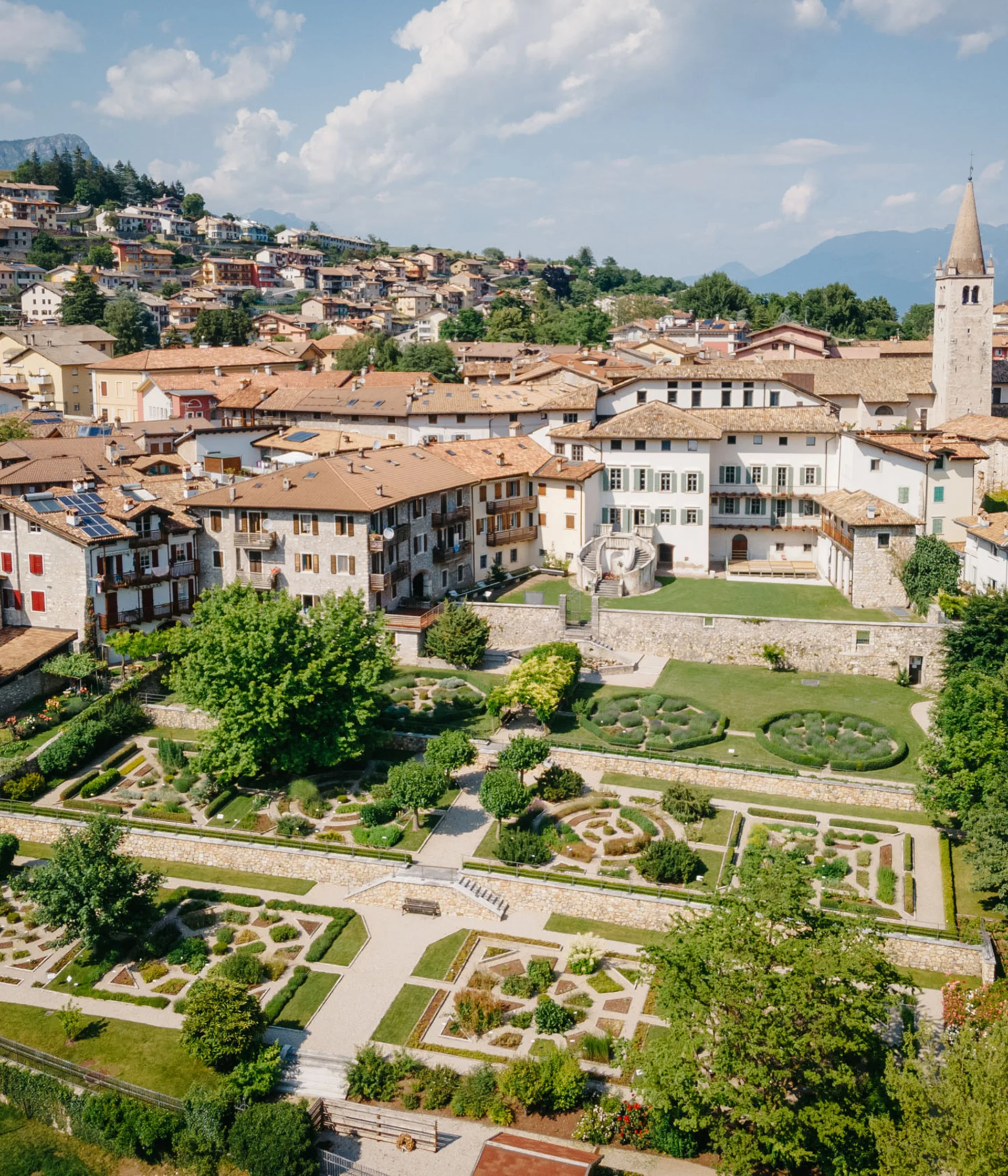 Tutto il divertimento di un hotel sul Monte Baldo Veduta aerea di un borgo con giardini formali e case con tetti in tegole