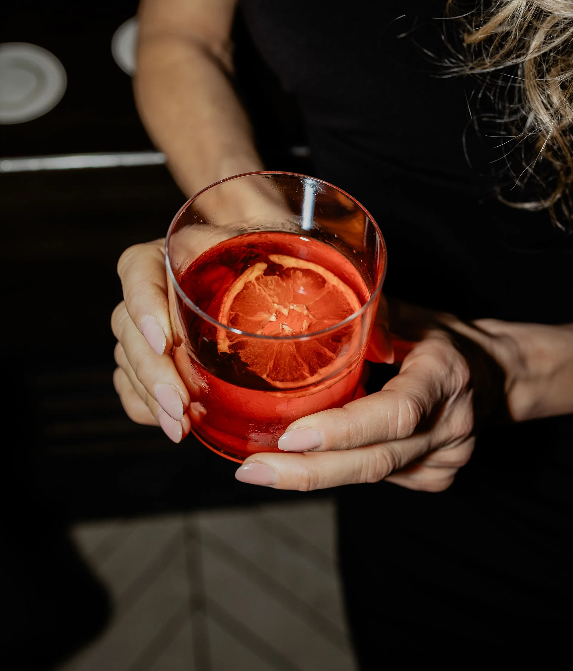 Il nostro ristorante a San Giacomo, Brentonico Donna che tiene un bicchiere con cocktail rosso e fetta di agrume