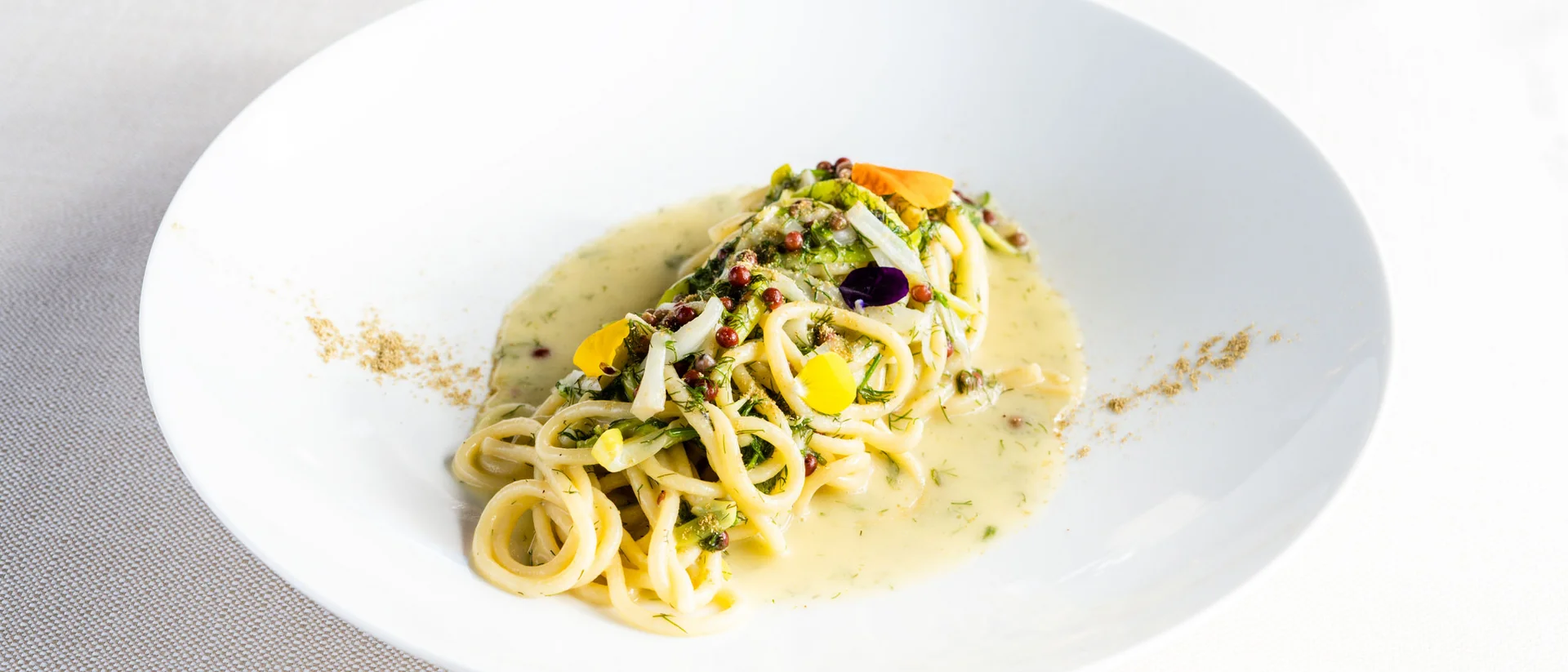 Il nostro ristorante a San Giacomo, Brentonico piatto di pasta con salsa cremosa e decorazioni di fiori ed erbe
