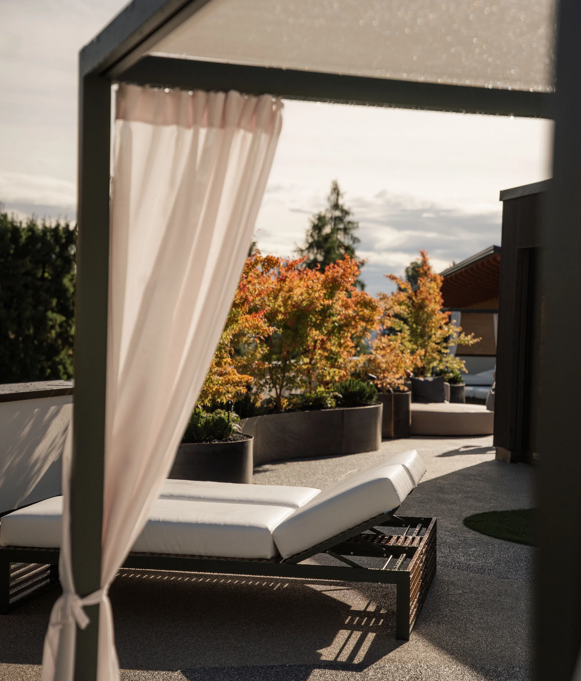 Elgus: hotel con spa a Brentonico lettino da sole bianco su terrazza con piante autunnali e tenda bianca