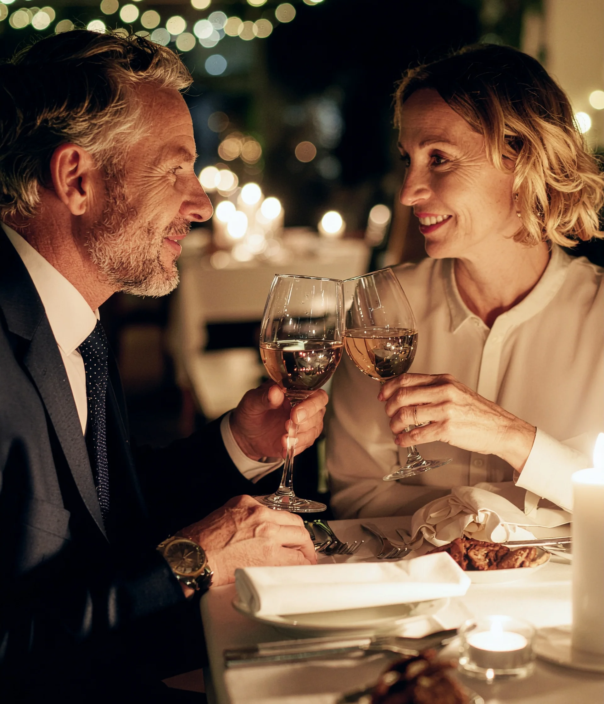 Il nostro ristorante a San Giacomo, Brentonico Coppia che brinda con calici di vino in un ristorante elegante con luci soffuse