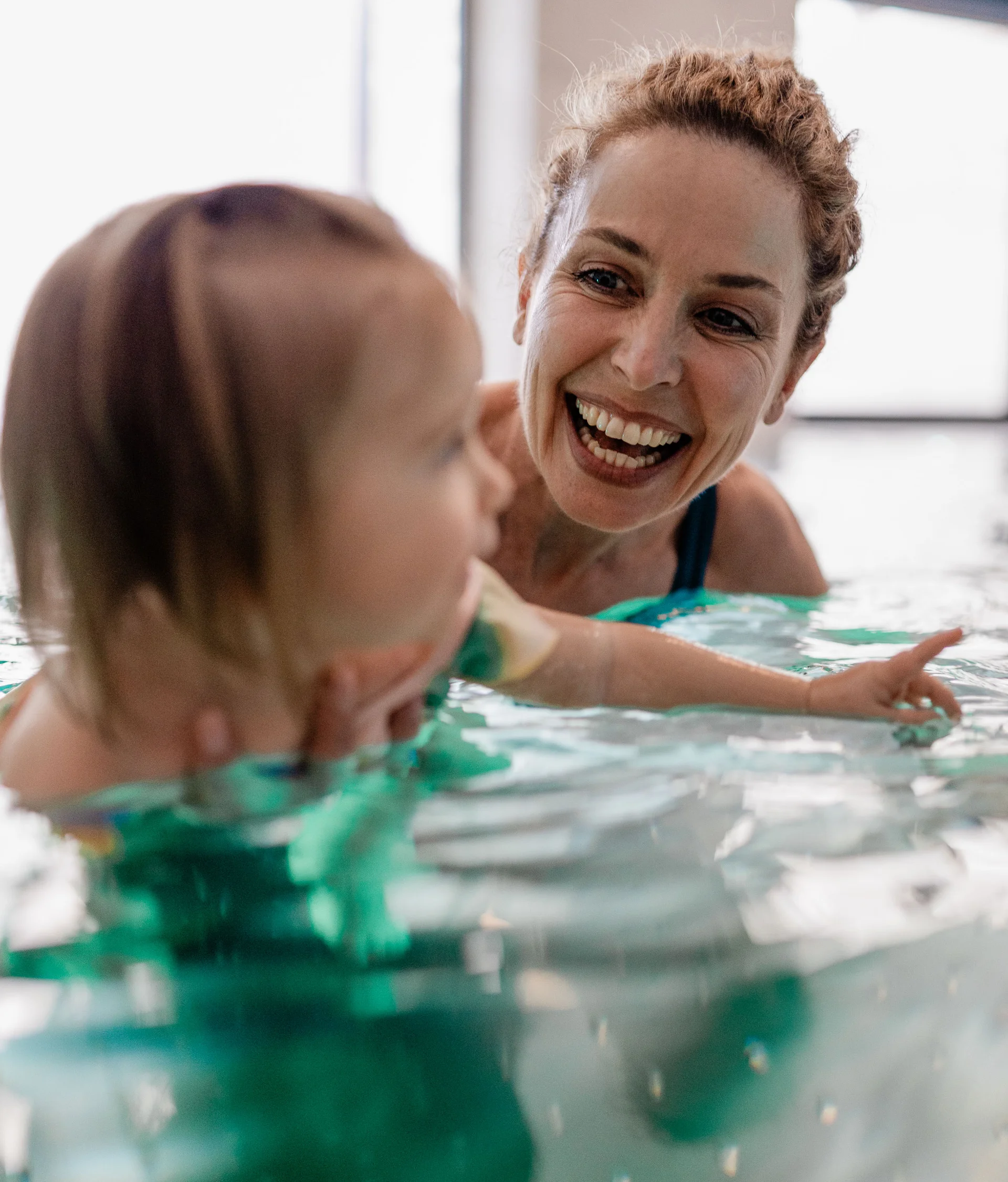 Elgus: hotel con spa per famiglie in Trentino Donna sorridente insegna a nuotare a un bambino in piscina