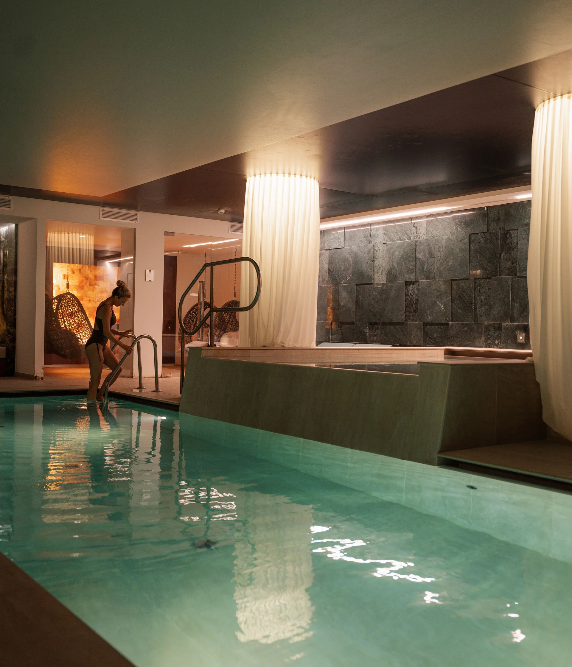 Elgus: hotel con spa a Brentonico Piscina interna con donna che entra nell'acqua e luci soffuse