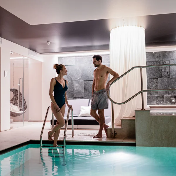 Le foto dell’Elgus Nature Retreat Coppia che parla vicino a una piscina interna in un ambiente moderno e rilassante