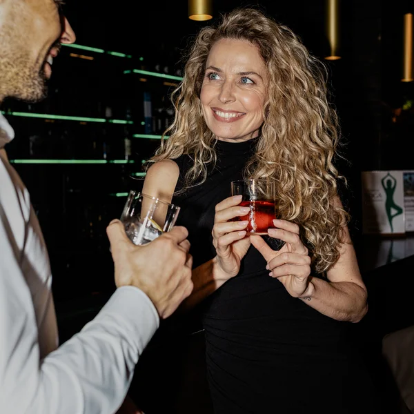 Le foto dell’Elgus Nature Retreat Donna sorridente con capelli ricci biondi che tiene un bicchiere rosso al bar