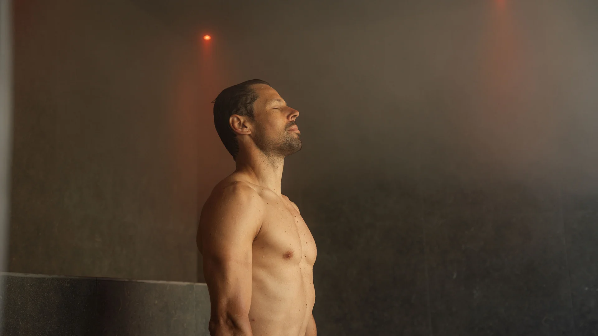 Hotel per single in Trentino Uomo rilassato in sauna con occhi chiusi e luce soffusa