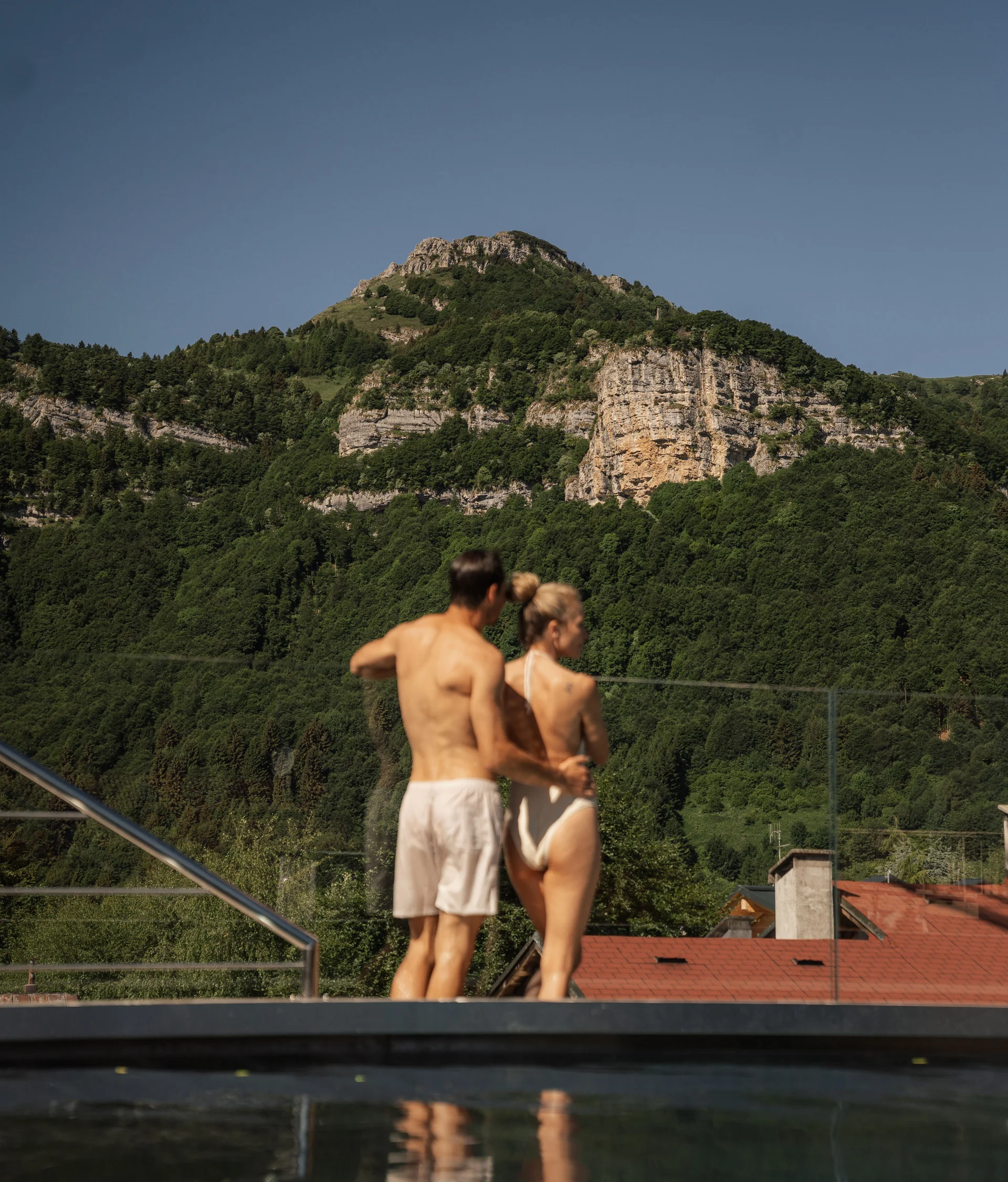 Il Forest Rooftop dell’Elgus Coppia in costume da bagno davanti a una piscina con vista sulle montagne verdi