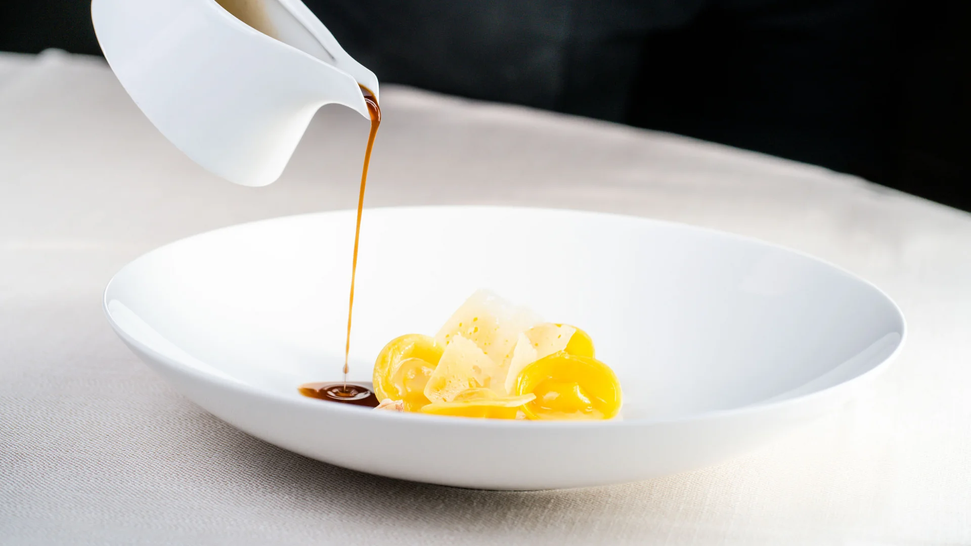 Salsa scura versata su pasta ripiena in piatto bianco