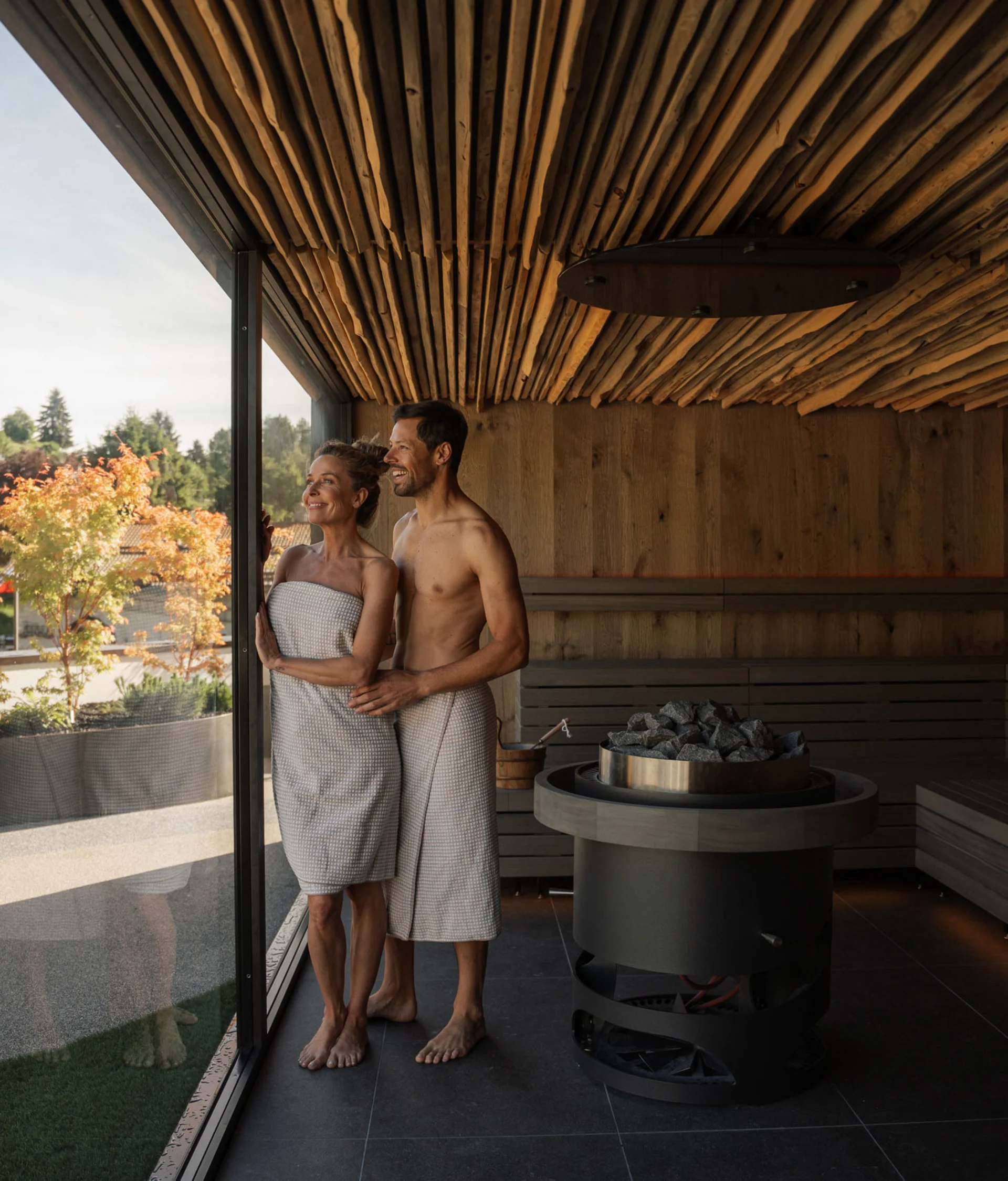 Il Forest Rooftop dell’Elgus Coppia in accappatoi nella sauna con vista sul paesaggio autunnale