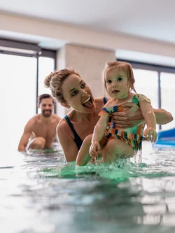 Famiglia che gioca e si diverte in piscina coperta