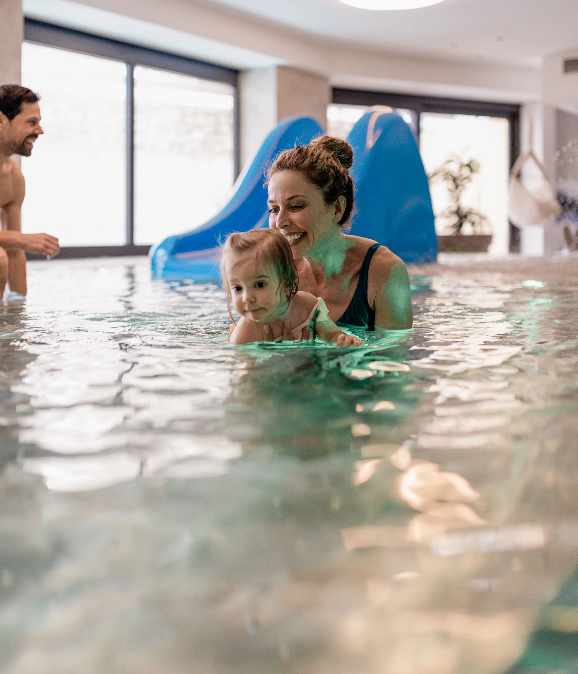 Elgus: family hotel a Brentonico Bambino e donna che giocano in piscina coperta con scivolo blu