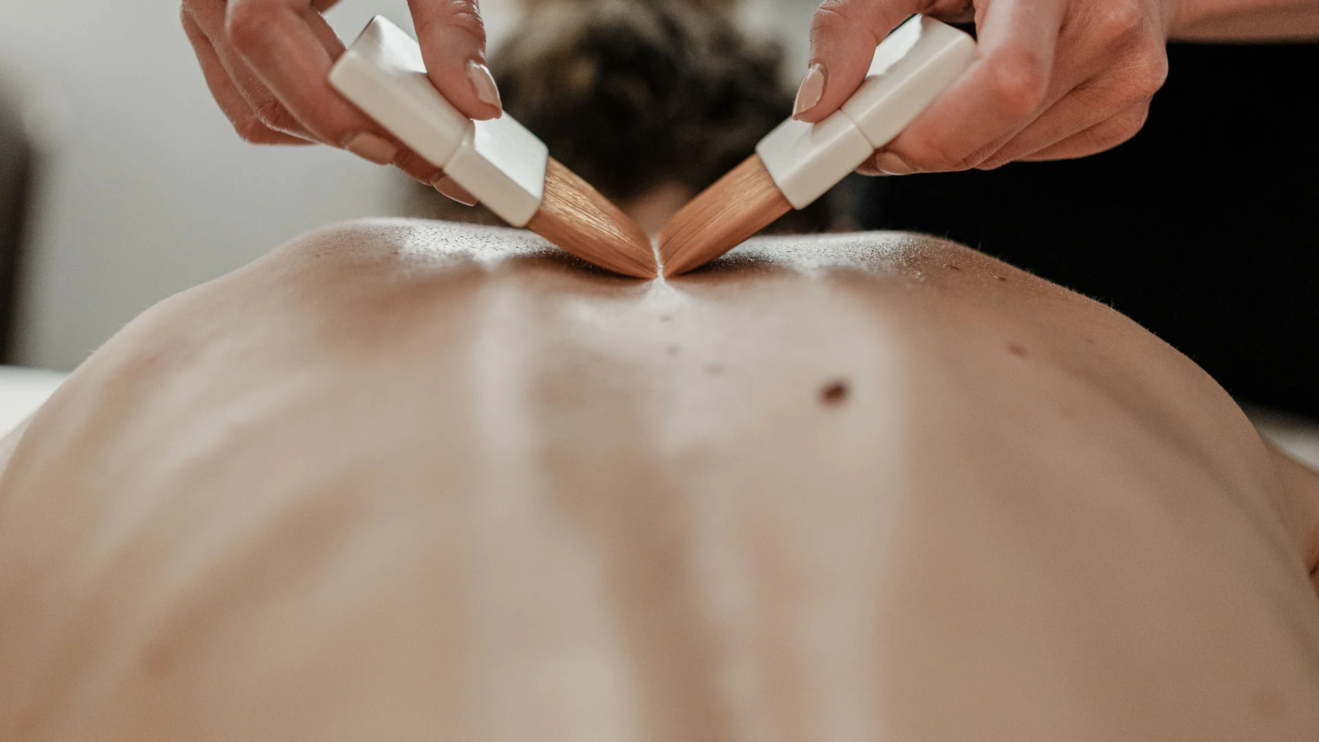 Trattamenti e massaggi in Trentino Massaggio sulla schiena con due pennelli tenuti da una persona