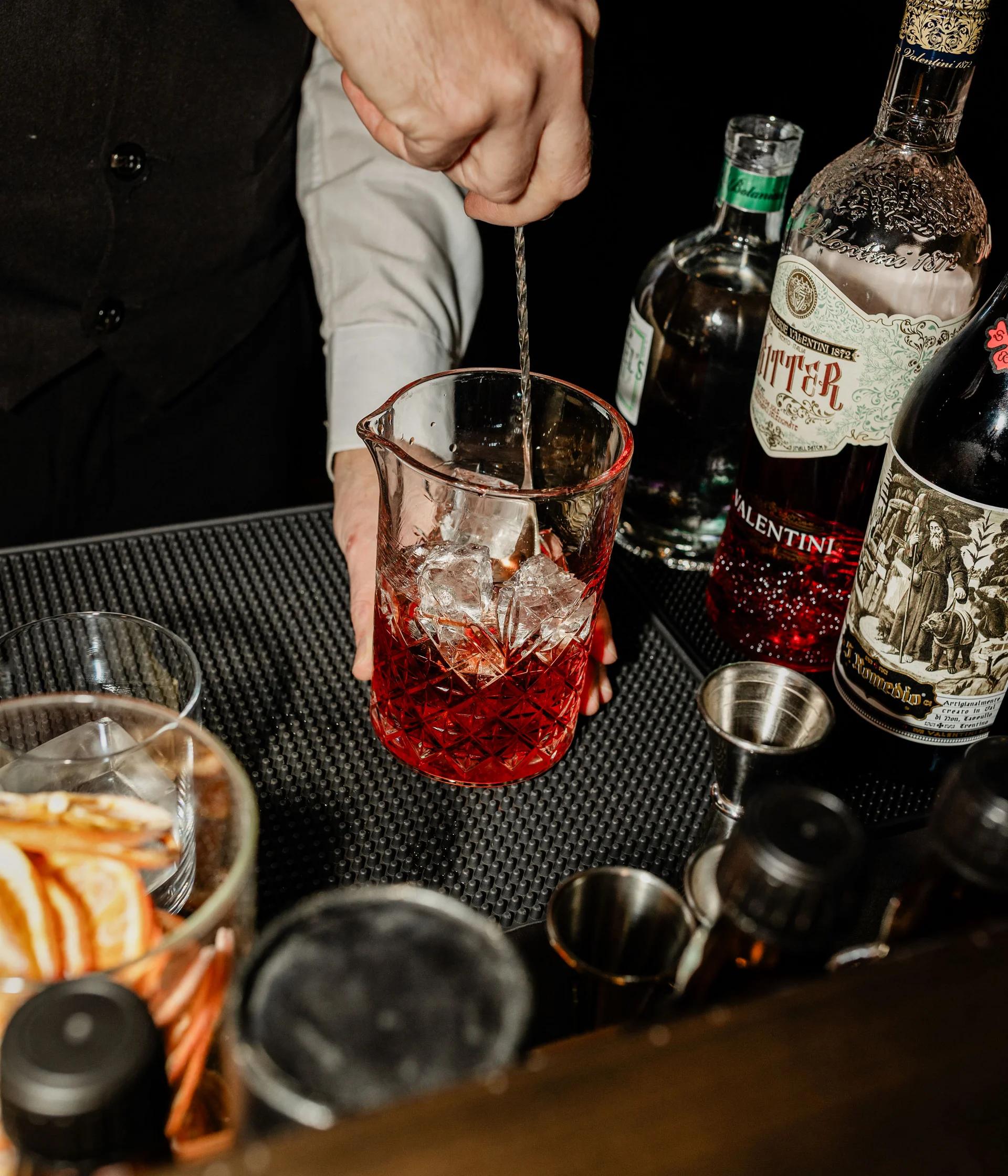 Lounge bar e bistrot a San Giacomo Bartender che mescola un cocktail rosso con ghiaccio in un mixing glass