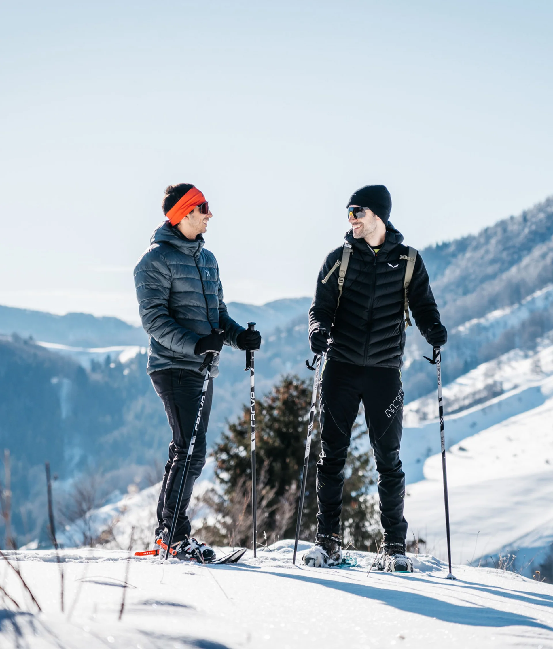 Tutto il divertimento di un hotel sul Monte Baldo Due uomini con abbigliamento invernale e sci da fondo in montagna innevata