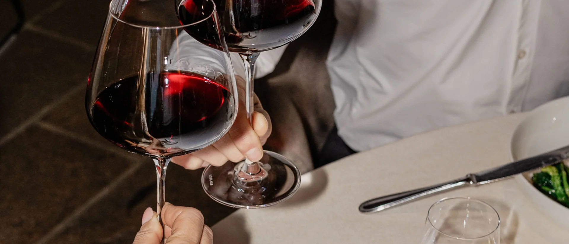 Il nostro ristorante a San Giacomo, Brentonico Due persone brindano con bicchieri di vino rosso a cena