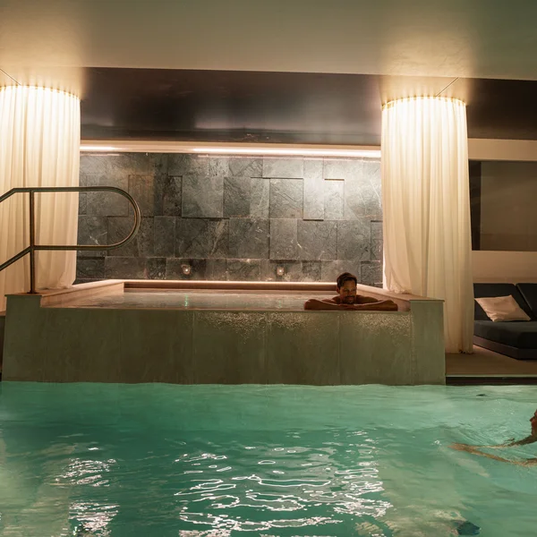 Le foto dell’Elgus Nature Retreat Piscina interna con persona che nuota e vasca idromassaggio con uomo rilassato
