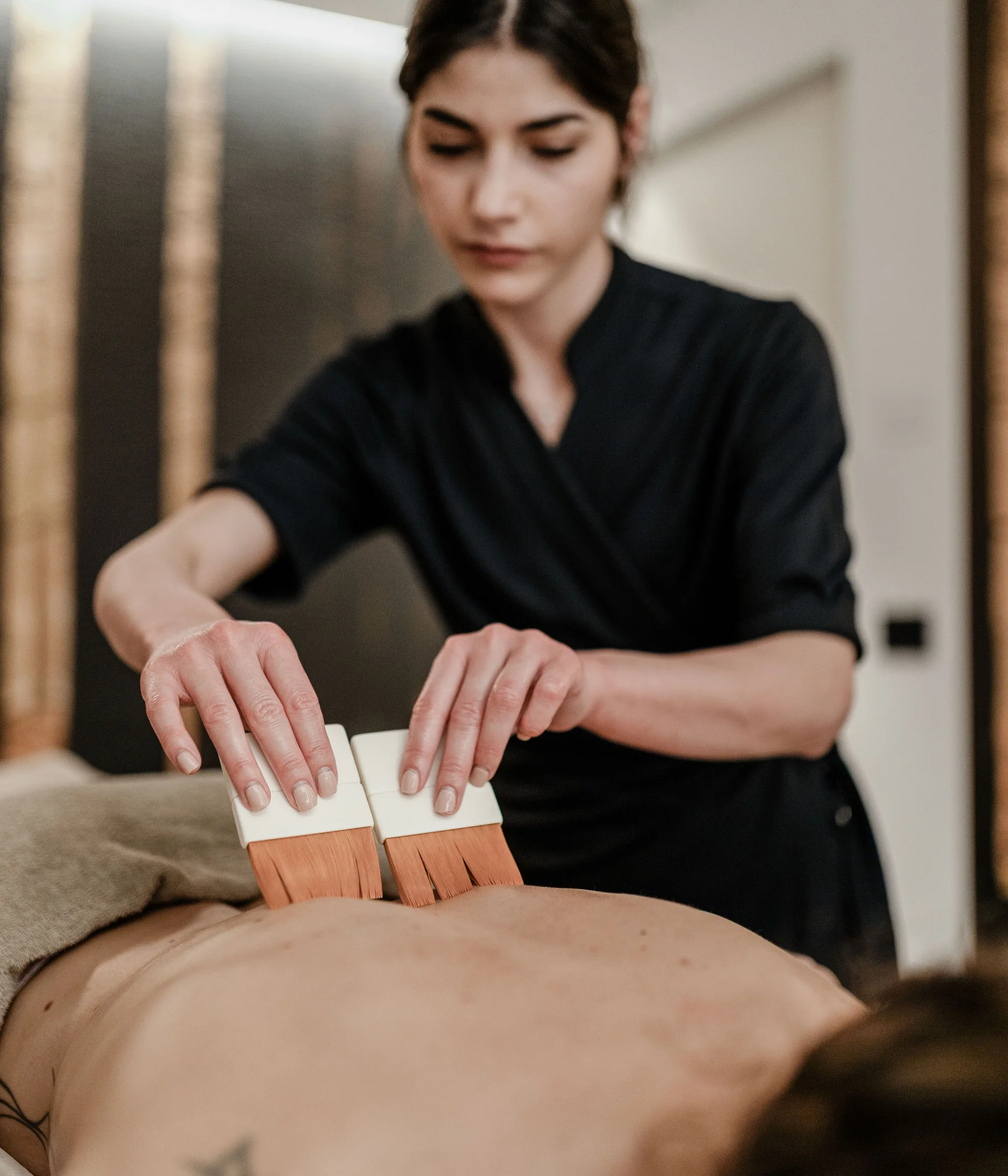 Elgus: hotel con spa a Brentonico Massaggiatrice che esegue un massaggio con pennelli sul dorso di un cliente