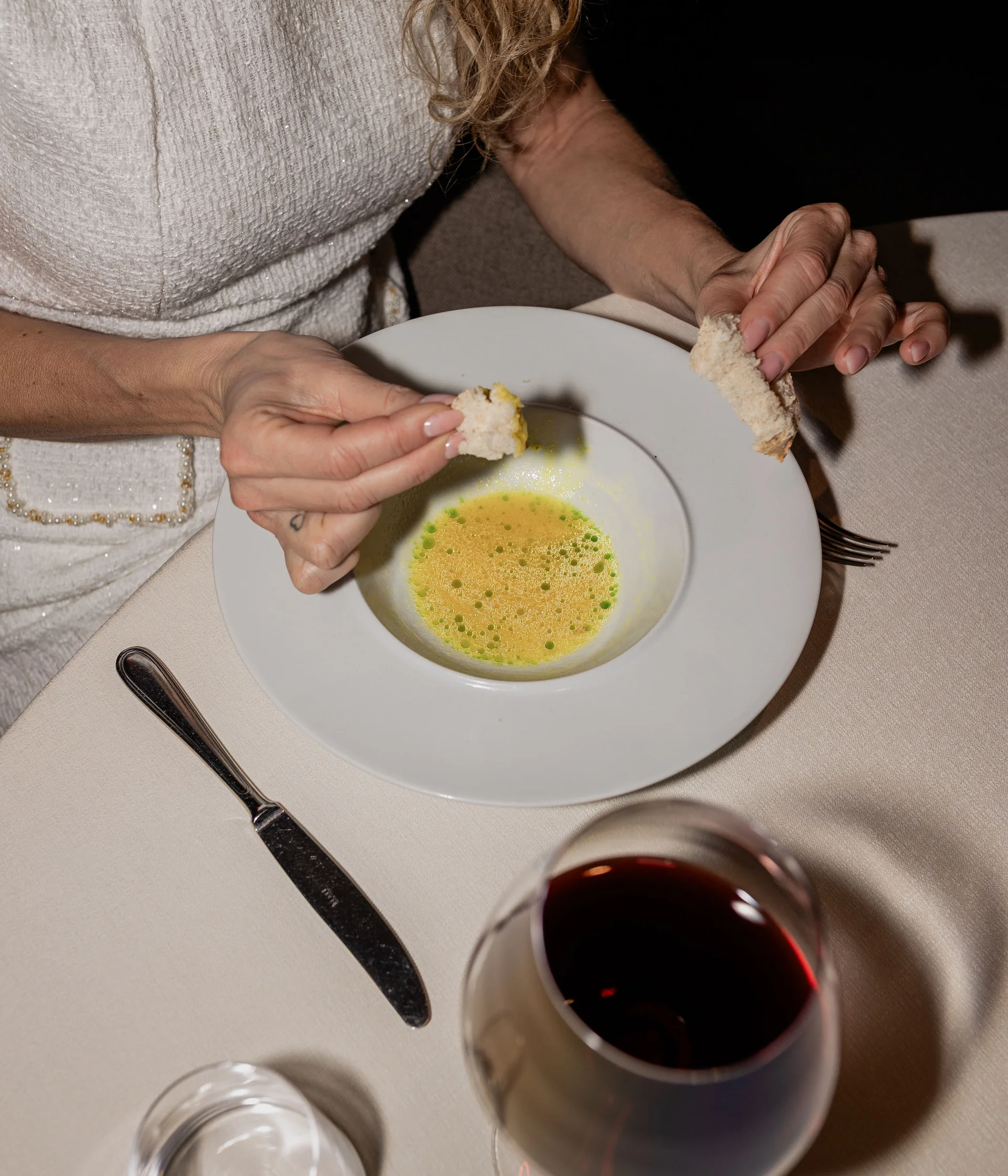 Elgus: hotel in Trentino con pensione ¾ Donna che intinge pane in una zuppa gialla con gocce verdi in un piatto bianco
