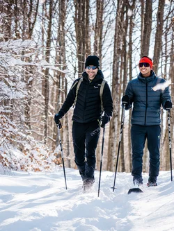 Due uomini che camminano con racchette da neve in una foresta innevata