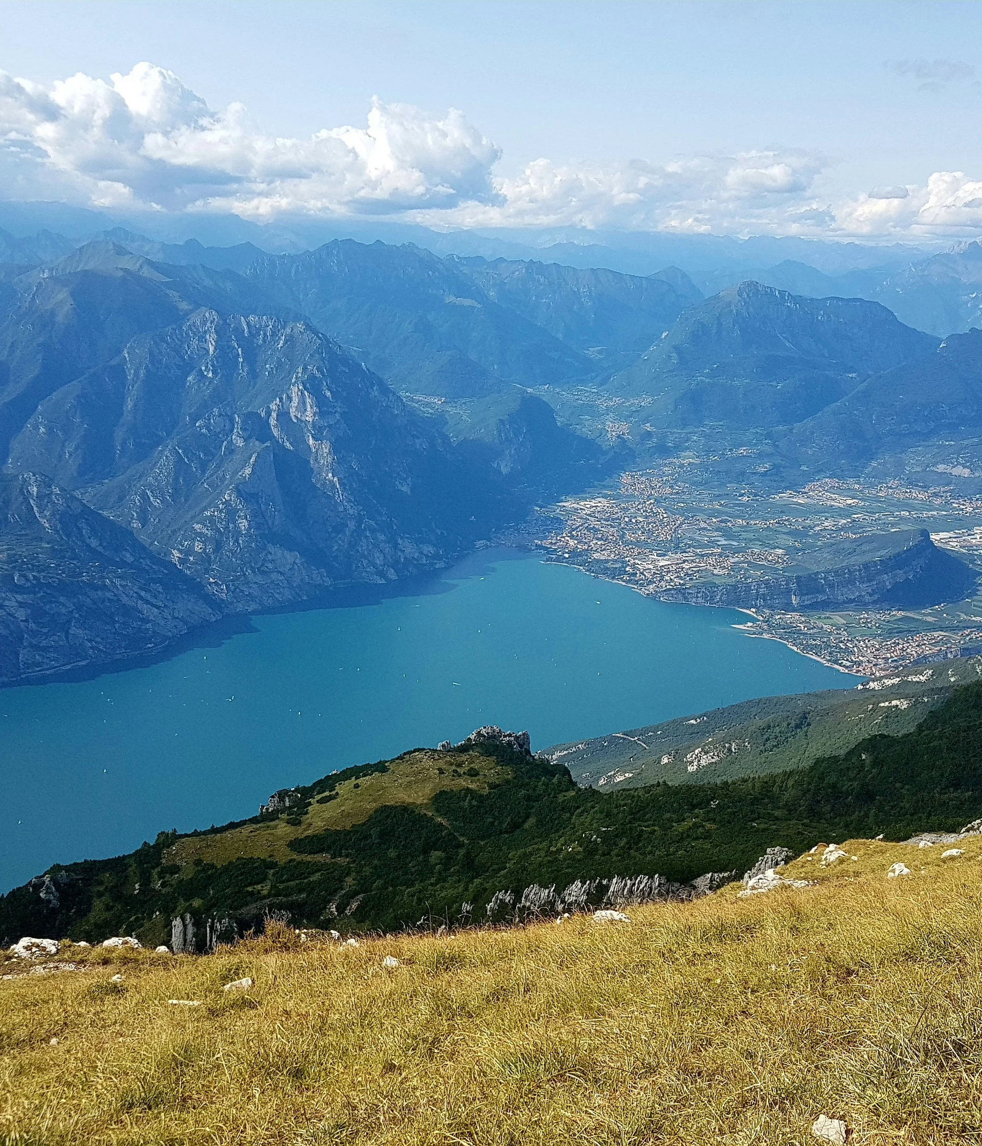 Tutto il divertimento di un hotel sul Monte Baldo Vista panoramica del lago circondato da montagne e prato in primo piano