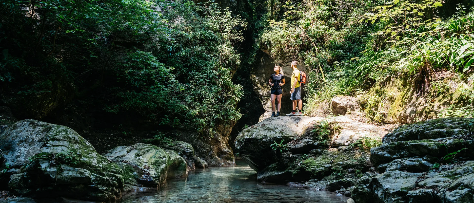 Tutto il divertimento di un hotel sul Monte Baldo Due escursionisti su una roccia vicino a un fiume in una foresta verde