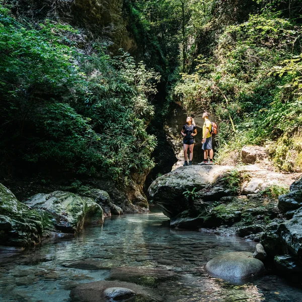 Le foto dell’Elgus Nature Retreat Due escursionisti su una roccia vicino a un fiume in una foresta verde