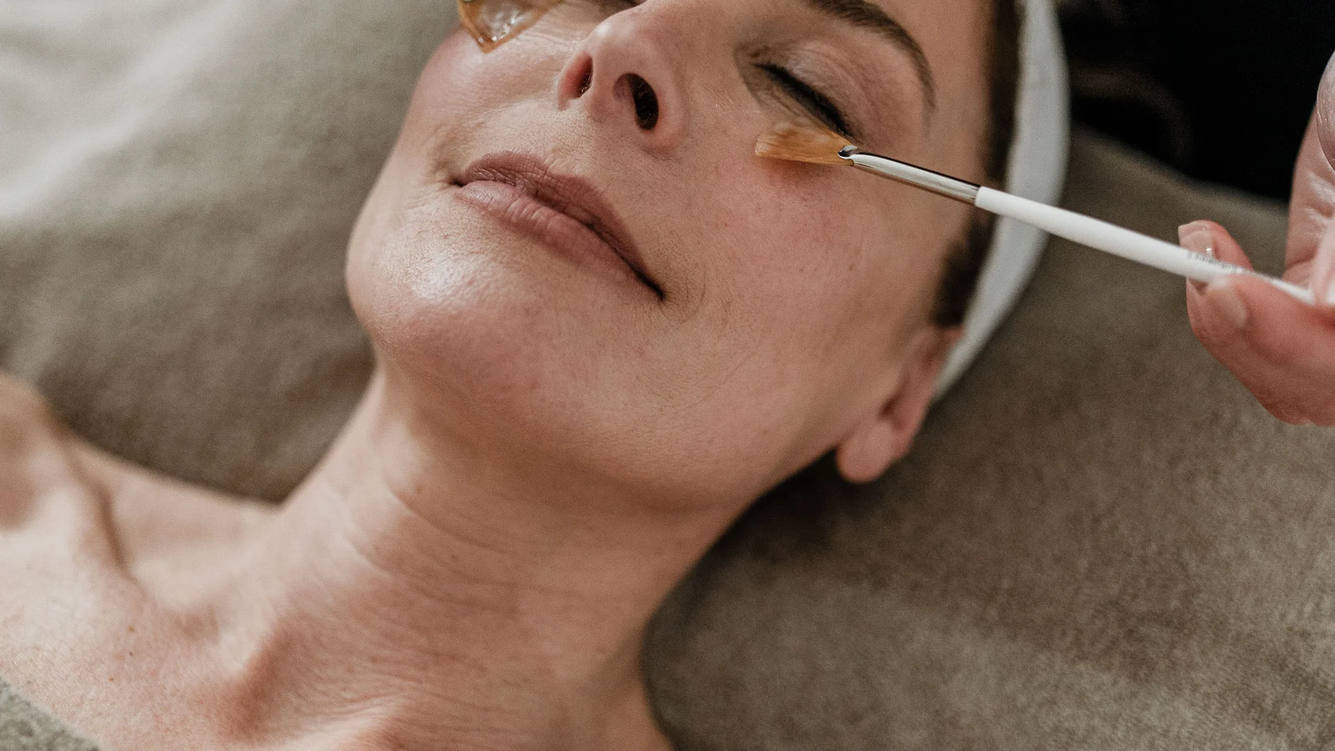 Trattamenti e massaggi in Trentino Donna che riceve un trattamento viso con maschera applicata con pennelli
