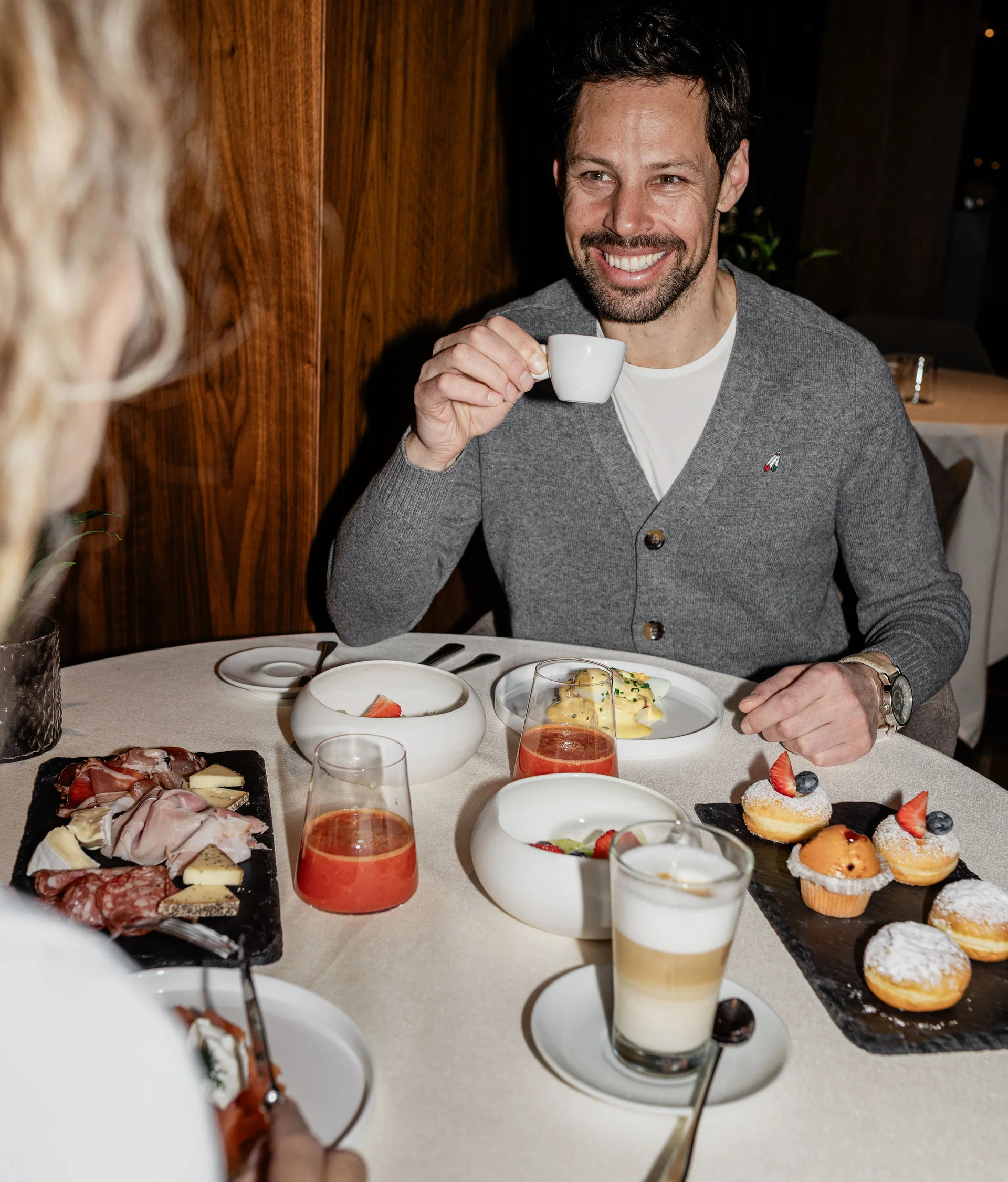 Il nostro ristorante a San Giacomo, Brentonico Uomo sorridente che beve caffè a colazione con dolci e succhi sul tavolo