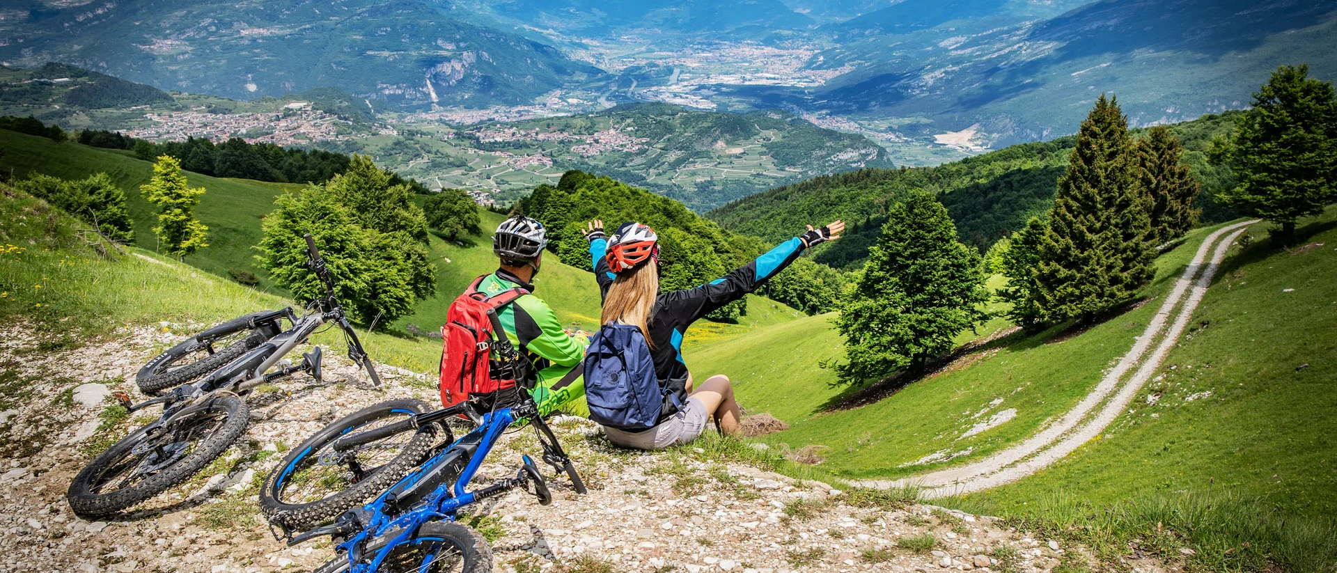 Tutto il divertimento di un hotel sul Monte Baldo Due ciclisti seduti su una collina con vista panoramica sulle montagne e vallate