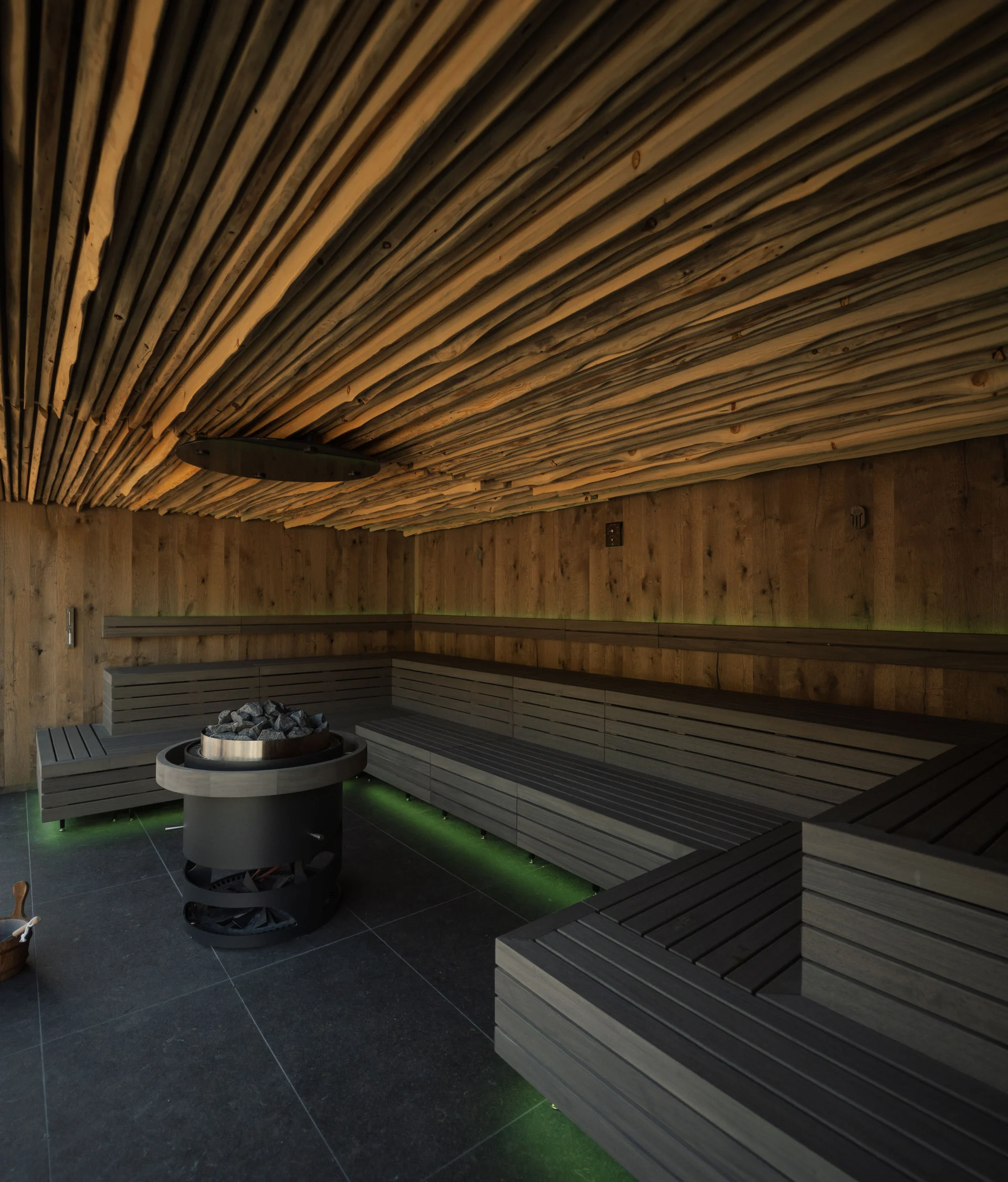 Elgus: hotel con spa a Brentonico Interno di una sauna con panche in legno e riscaldatore centrale con pietre