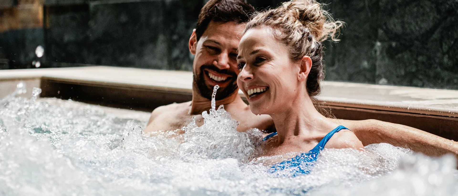 Elgus: hotel con spa a Brentonico Coppia felice rilassata in una vasca idromassaggio con acqua frizzante