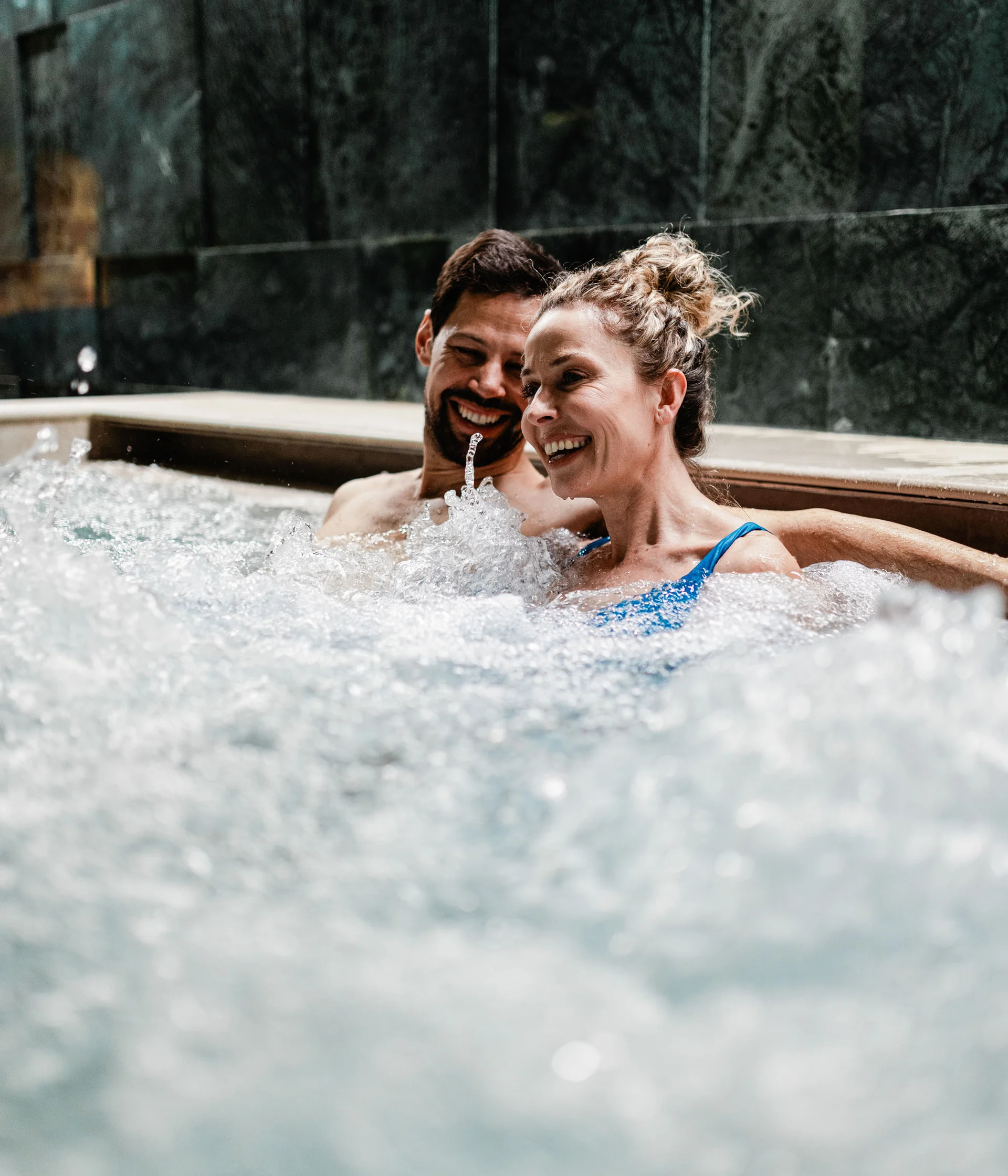 Elgus: hotel con spa adults only in Trentino Coppia felice rilassata in una vasca idromassaggio con acqua frizzante