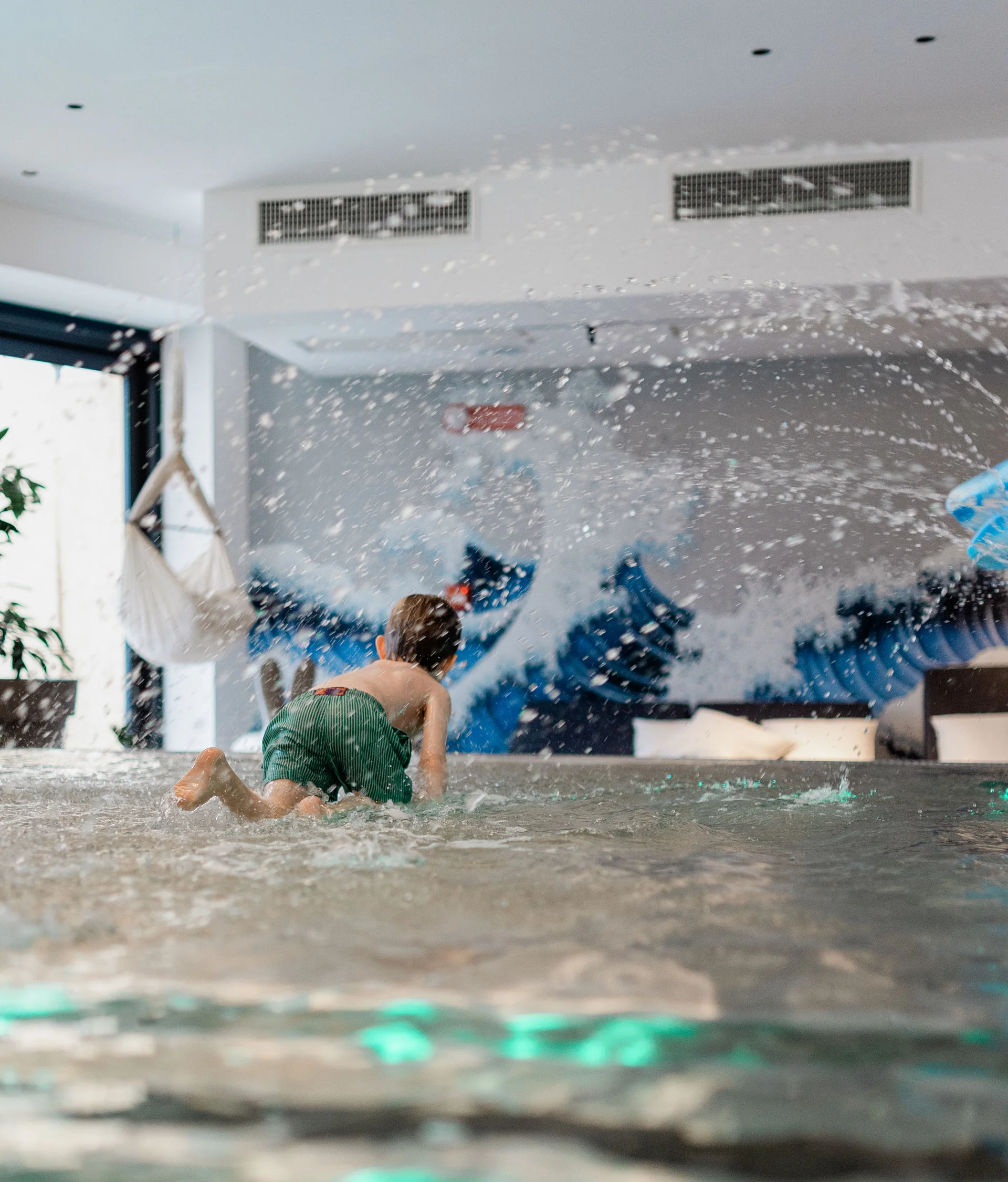 Elgus: hotel con spa per famiglie in Trentino Bambino che gioca in una piscina interna con schizzi d'acqua