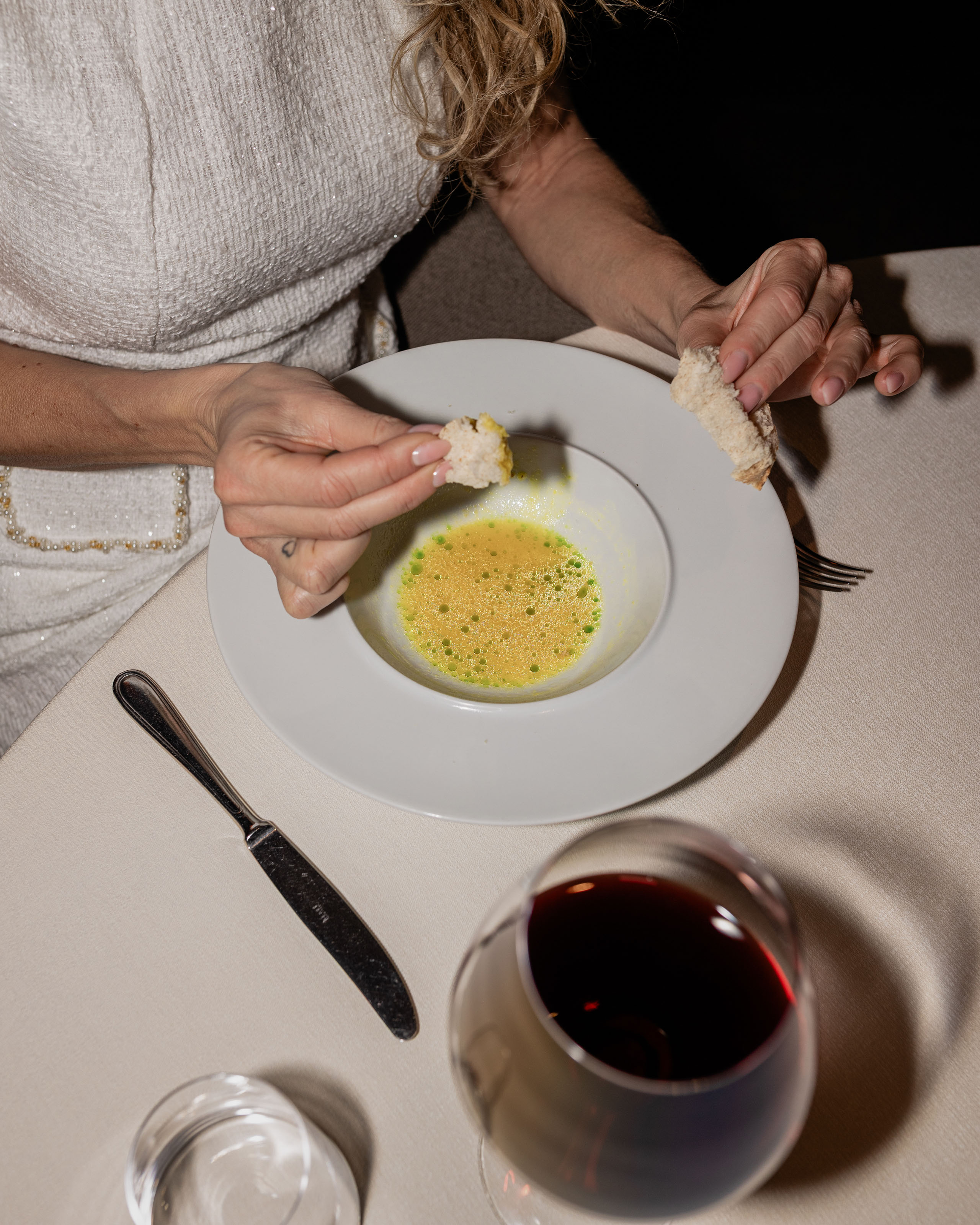 Le foto dell’Elgus Nature Retreat Donna che intinge pane in una zuppa gialla con gocce verdi in un piatto bianco