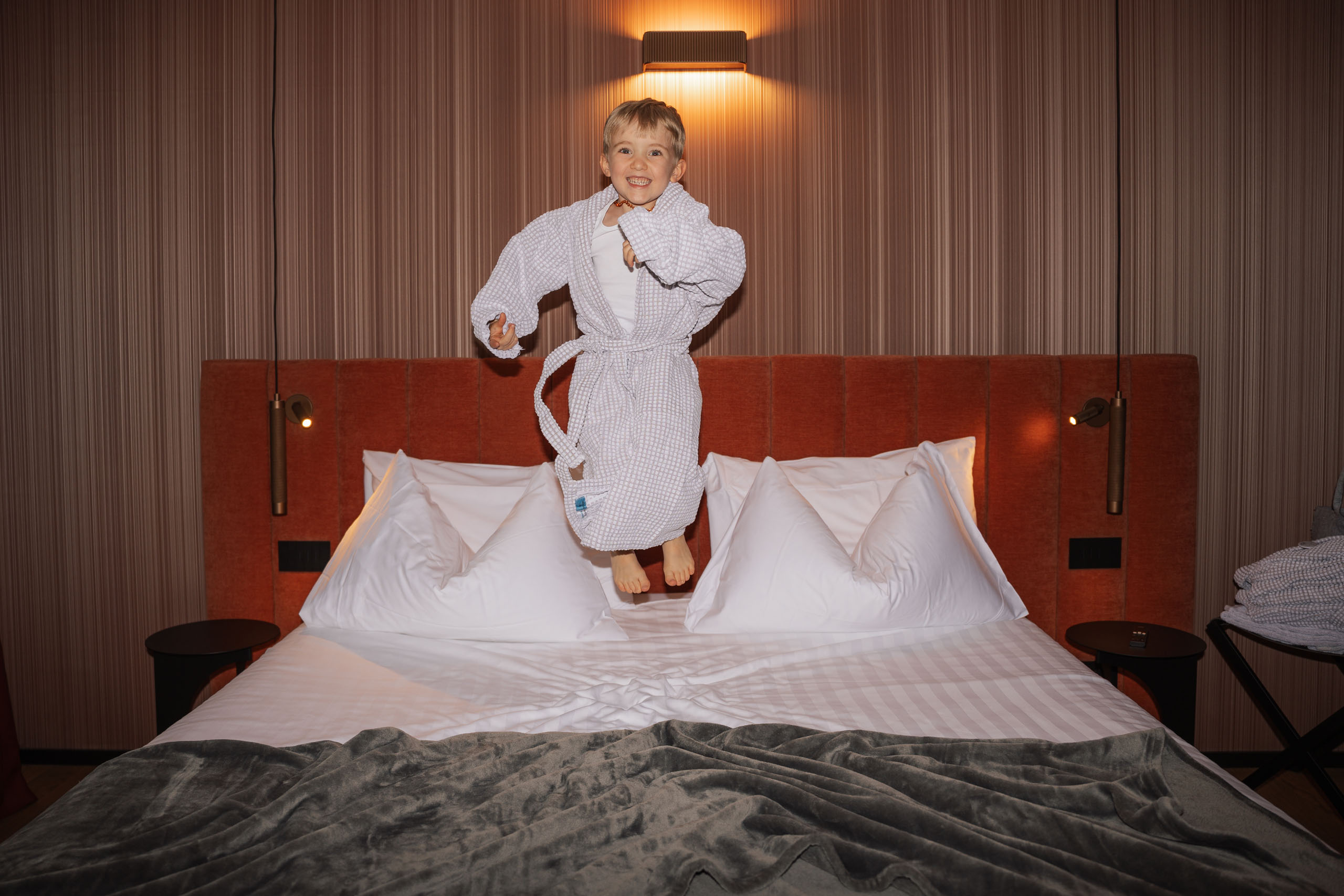 Elgus: hotel in San Giacomo, Brentonico Child jumping on a bed in a modern hotel room