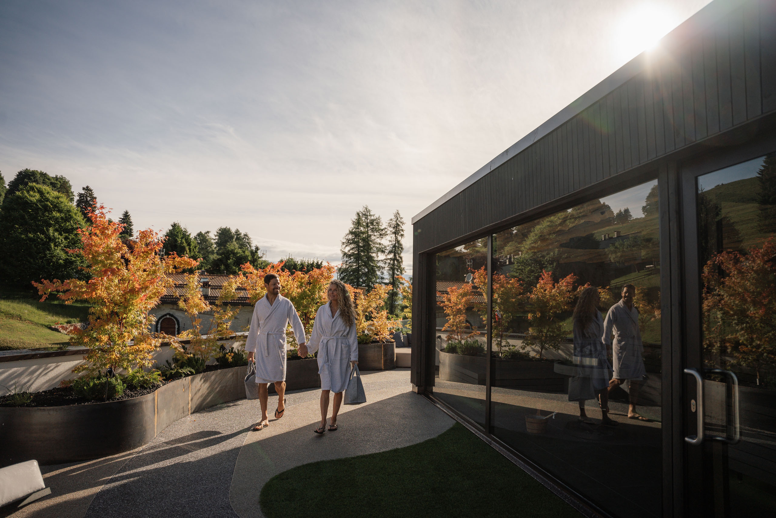 Le foto dell’Elgus Nature Retreat Coppia in accappatoi che cammina all'aperto vicino a edificio con vetrate
