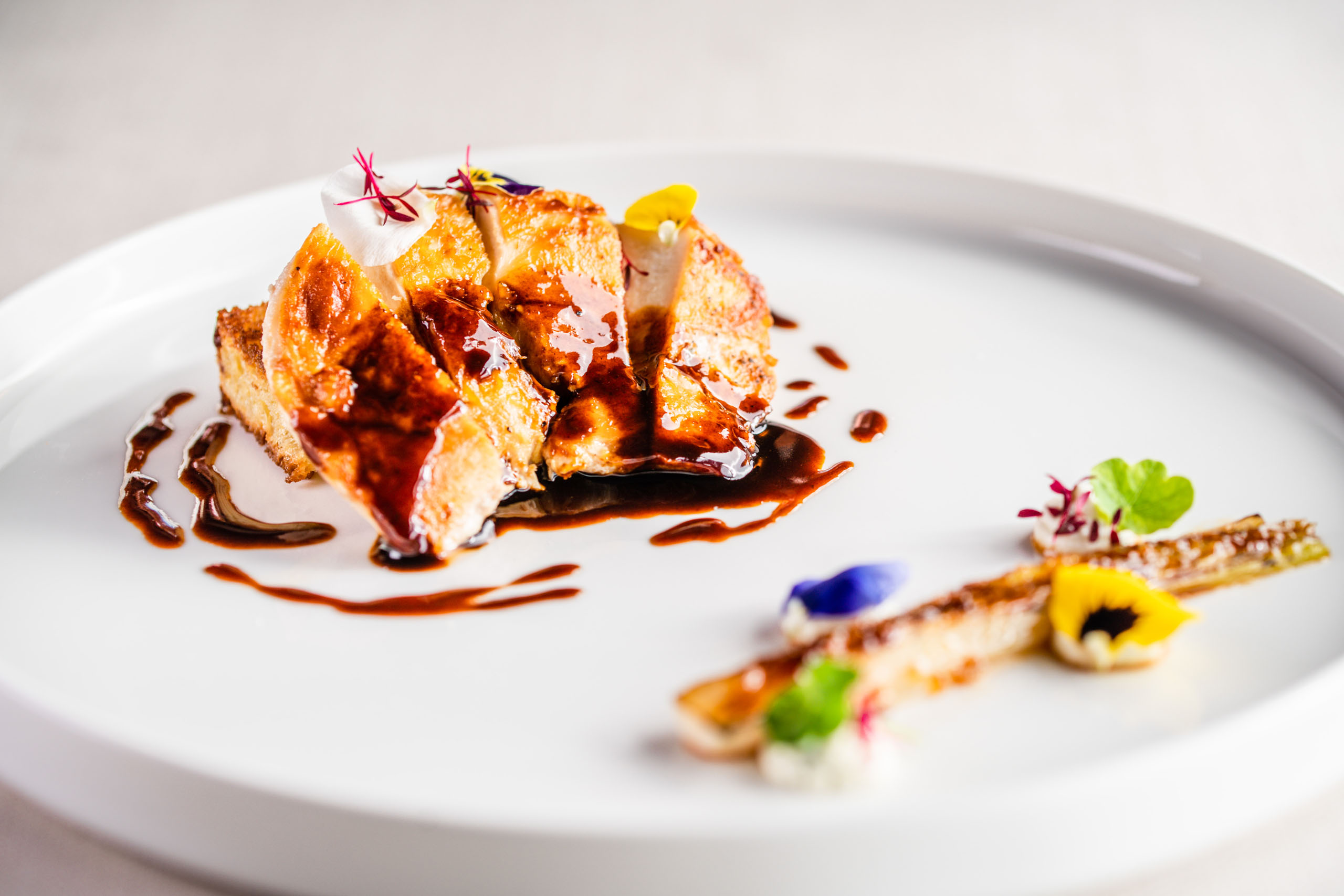 Le foto dell’Elgus Nature Retreat Piatto gourmet con carne glassata e decorazioni floreali su piatto bianco